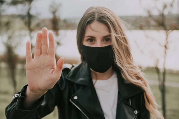 Kvinde i medicinsk maske viser stop tegn - Stock-foto