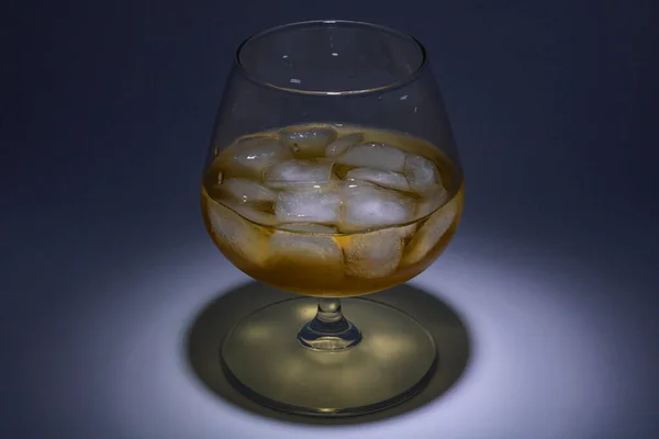 Un bicchiere di whisky con ghiaccio. Installazione artistica con illuminazione da — Foto Stock