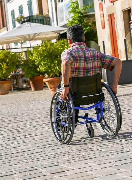 Disabled man rolling down the street in his wheelchair — Stock Photo, Image