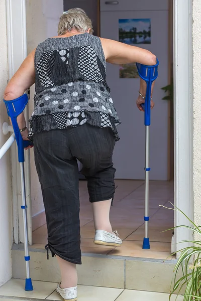 Mujer mayor con muletas — Foto de Stock