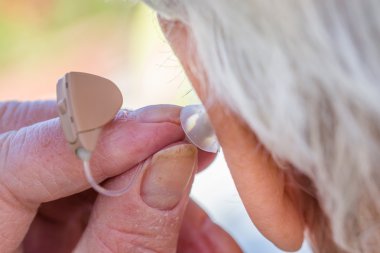üst düzey kadın onun kulaklarında işitme cihazı ekleme