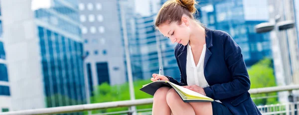 Dinámica joven ejecutiva tomando notas en su agenda —  Fotos de Stock