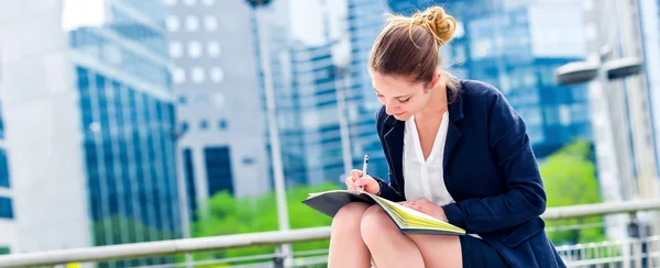 Dinámica joven ejecutiva tomando notas en su agenda — Foto de Stock