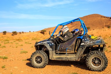 Merzouga, Fas - 26 Şubat 2016: Mavi Polaris Rzr 800 ve pilotlar Fas Merzouga çöl. Merzouga Sahra Güneydoğu Fas'ta bulunan küçük bir köydür. Merzouga ünlü için onun 