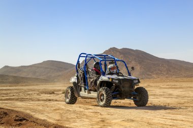 Merzouga, Fas - 24 Şubat 2016: Mavi Polaris Rzr 800 ve pilotlar Fas Merzouga çöl. Merzouga Sahra Güneydoğu Fas'ta bulunan küçük bir köydür. Merzouga ünlü için onun 