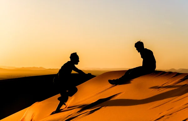 Genç adam onun arkadaşı bir kumul sahara üzerinde teşvik eder. — Stok fotoğraf