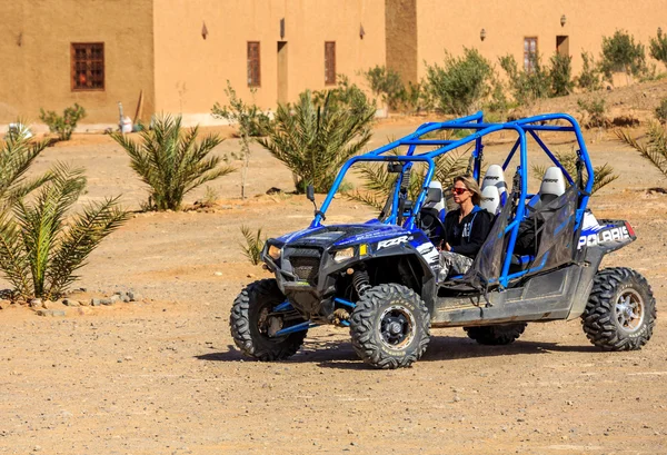 Itrane, Morocco - Feb 24, 2016: blue Polaris RZR 800 with woman pilot in a small Berber village in Morocco desert near Merzouga — Stock Photo, Image