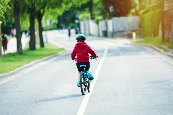 Niño pequeño haciendo la bicicleta solo en medio de la carretera — Foto de Stock