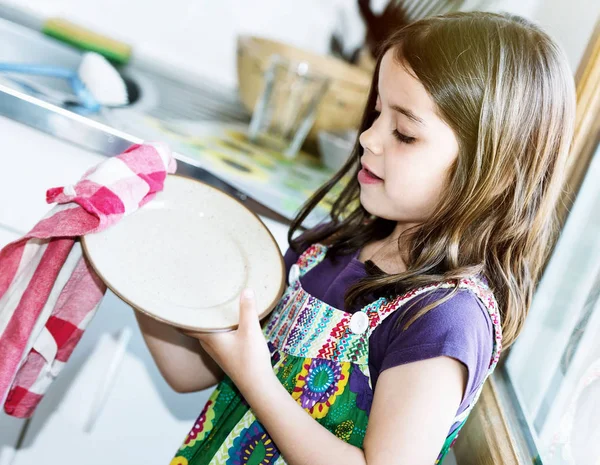 Muito bonito criança menina limpando os pratos — Fotografia de Stock
