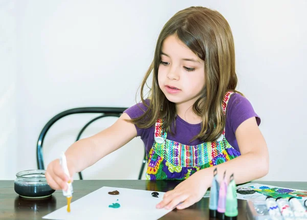 Retrato de menina bonito concentrado enquanto pintura — Fotografia de Stock