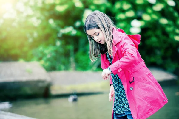 Bonita niña jugando en una roca en el borde del agua — Foto de Stock