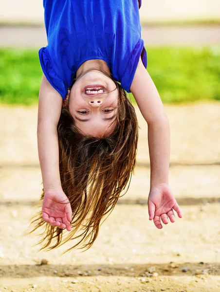 Kid hanging upside down on the monkey bars — Stock Photo, Image