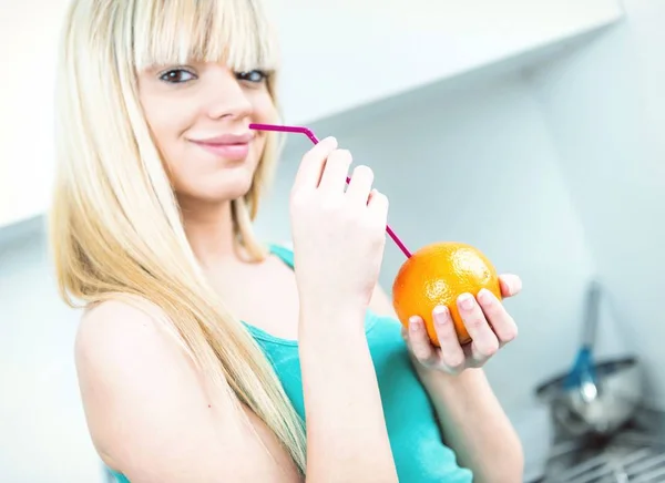 Charmante meisje een oranje drinken uit een rietje — Stockfoto