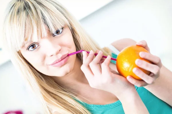 Chica guapa bebiendo una naranja de una paja —  Fotos de Stock