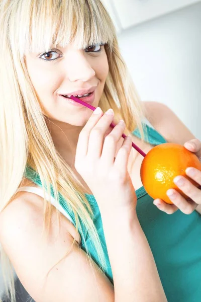 Дівчина п'є апельсин із соломи — стокове фото