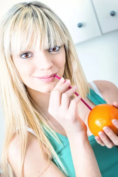 Linda chica bebiendo una naranja de una paja —  Fotos de Stock