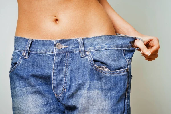 Woman with too large jeans after a diet — Stock Photo, Image