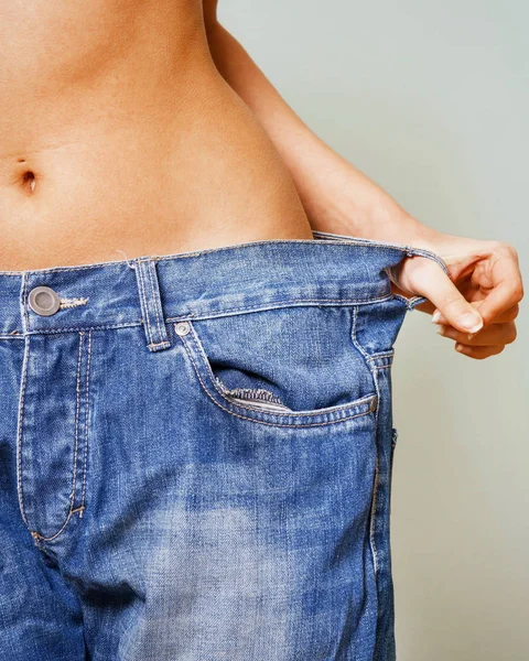 Brzuch kobiety w za dużych spodniach z bliska — Zdjęcie stockowe