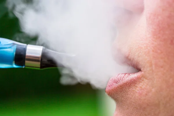 En kvinna som andas in från en elektronisk cigarett — Stockfoto