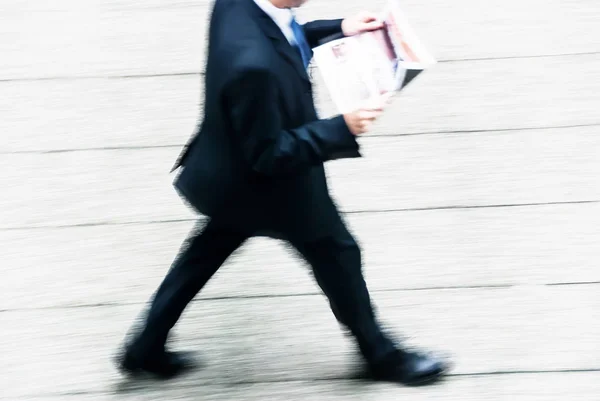 Wazig te bekijken van zakenman wandelen door het lezen van de krant — Stockfoto