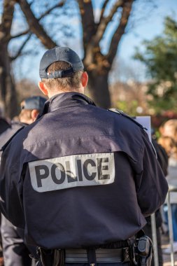 Paris, France - October 26, 2012:Close-up on a French policeman ensuring the safety of citizens on the street, back view on his uniform clipart