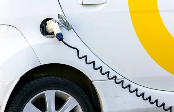 Coche eléctrico siendo cargado. Carga de un coche eléctrico con la fuente de alimentación enchufada . — Foto de Stock