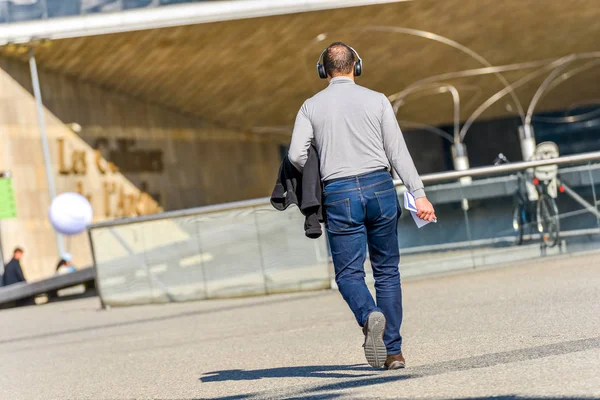 La defense, France- April 10, 2014:Back view of a young man with headphones listening to music in the city streets — Stock Photo, Image