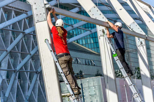 La defense, Frankrike-10 April 2014: två arbetare klättring på metall stegar på en byggarbetsplats — Stockfoto