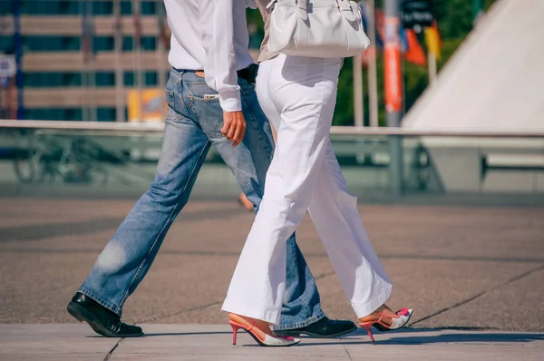 La defense, França - 30 de agosto de 2006: Casal elegante andando em uma rua. O homem está vestindo jeans azuis e a mulher calça branca e sapatos bonitos pés — Fotografia de Stock