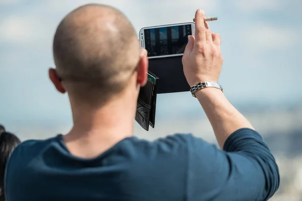 Paris, Frankrijk - 30 juni 2013: man neemt een foto van de monumenten van Parijs met zijn telefoon, vanaf de bovenkant van de heuvel van montmartre — Stockfoto