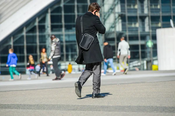 La défense, France- 09 avril 2014 : vue de côté d'un homme d'affaires marchant dans une rue en téléphonant. Il porte un sac bandoulière. — Photo