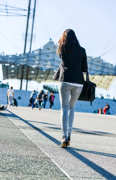 La défense, France- 09 avril 2014 : portrait d'une femme brune décontractée marchant avec un sac sur une rue et des talons hauts — Photo