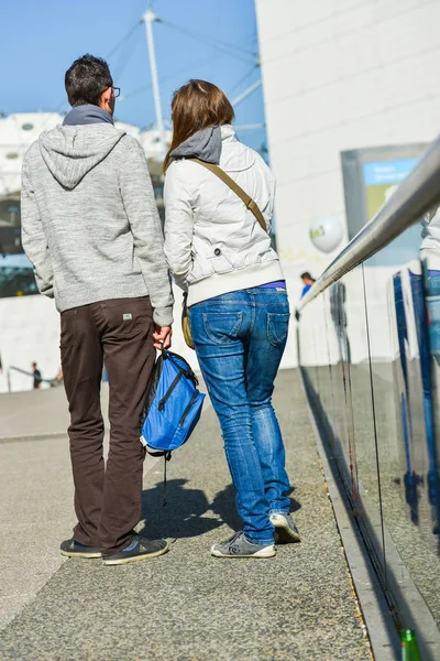 La defense, france- 10. April 2014: junges Paar läuft auf einer Straße. Das Mädchen trägt blaue Jeans und der Mann eine braune Hose — Stockfoto