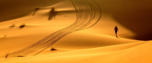 Merzouga, Maroko - 24. února 2016: Žena Treking podél horké pouště, krásné oranžové písečné duny, Sahara, aktivní dovolená, zkoumání, objevování přírody koncept — Stock fotografie