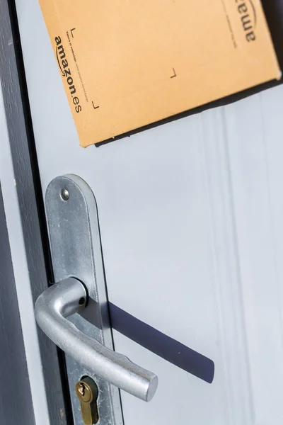 Париж, Франция - 8 февраля 2017 года: Amazon Prime Parcel Package Stuck on the door of a house. Amazon, is an American electronic commerce and cloud computing company, based in Seattle, Started as an onli — стоковое фото