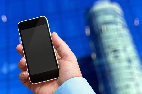 Smartphone in der Hand mit einem leeren Bereich, um ein benutzerdefiniertes Bild einzufügen. Modernes Gebäude im Hintergrund — Stockfoto