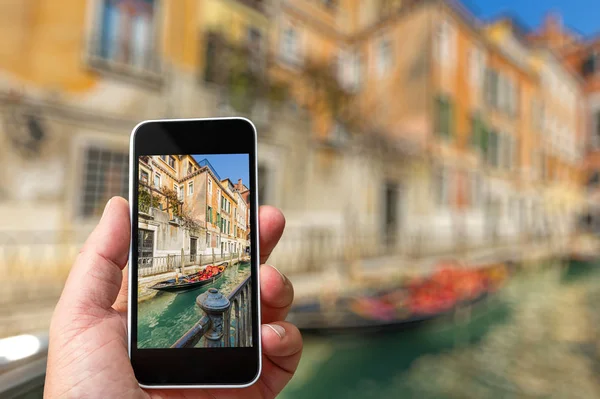 Homem tirando uma foto de um canal de Veneza com seu Smartphone na mão — Fotografia de Stock