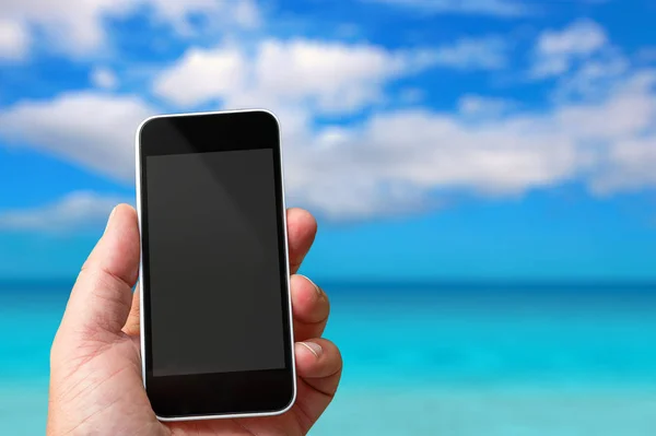 Смартфон в руке с пустой области для вставки пользовательского изображения. Парадизисное море на заднем плане — стоковое фото