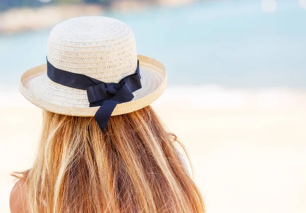 Vista posteriore di giovane donna con un cappello di paglia su sfondo spiaggia — Foto Stock