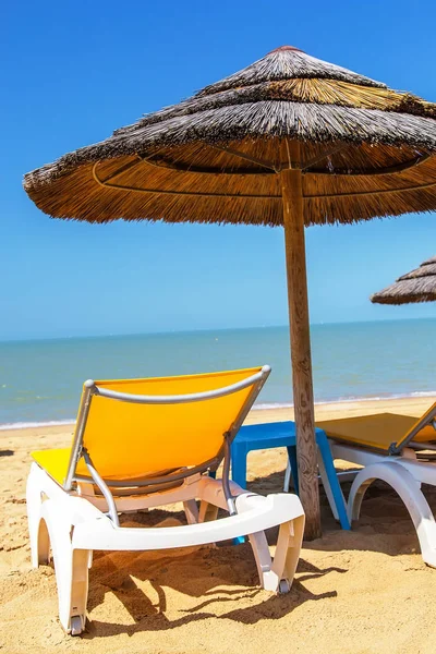 Parasoller och solstol på den tropiska stranden — Stockfoto