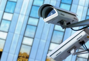 cctv security camera in a city with blury business building on background clipart