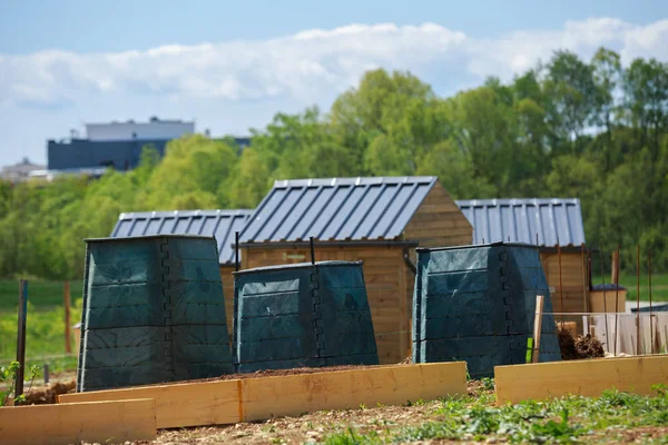 Zwarte kunststof compostbak en kleine houten hut in de tuin van de stad — Stockfoto