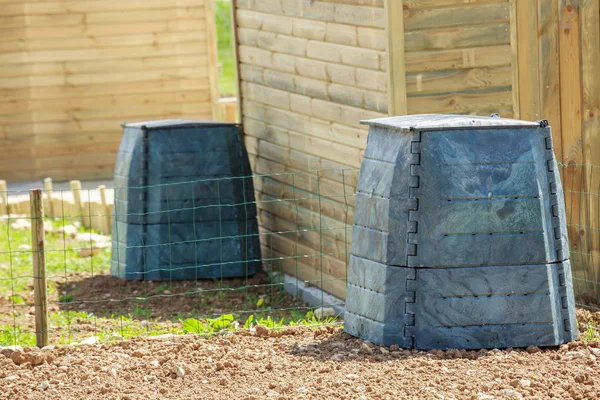 Black plastic compost bin and small wooden cabin in town garden — Stock Photo, Image