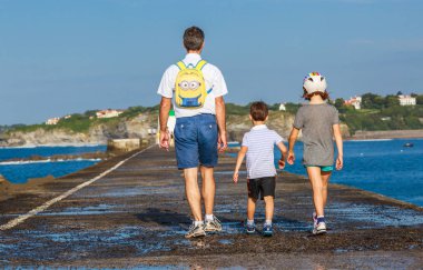 Ciboure, Fransa - 26 Eylül 2016: bekar baba ve iki çocuk çocuk oğlu ciboure liman iskelede yürüyüş aile.