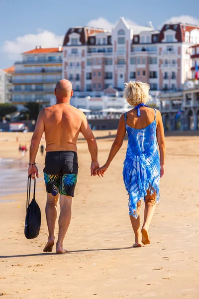 Saint-Jean de Luze, Francia - 28 de septiembre de 2016: pareja de mediana edad caminando juntos y tomados de la mano a lo largo de un paseo marítimo —  Fotos de Stock