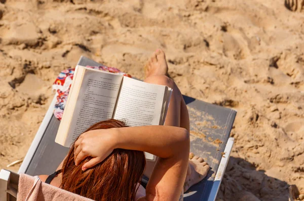 Saint-jean de luze, Frankreich - 28. September 2016: Frau liest ein Buch, das auf einem Liegestuhl am Strand liegt — Stockfoto