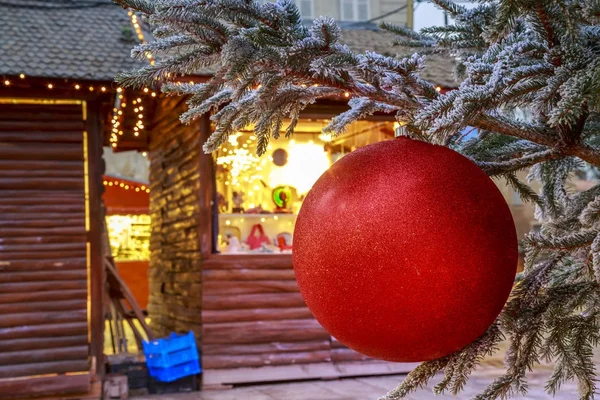 Niort, France - December 05, 2017:Close-up of a Christmas ball hanging on a snowy tree with Christmas market chalets in the background — Stock Photo, Image