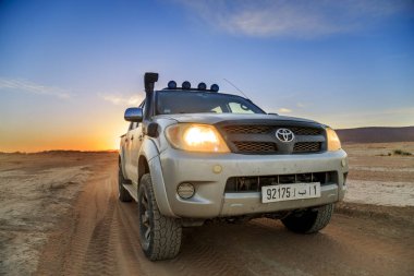 Ait Saoun, Morocco - February 23, 2016: Toyota Hilux on desert during sunset clipart