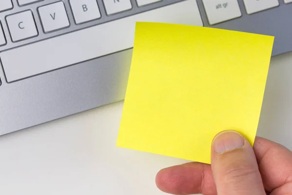 Mano humana sosteniendo nota adhesiva amarilla —  Fotos de Stock