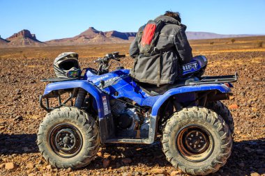 Bir adam çölde onun yanında onun kask ile a avlu üzerinde oturarak